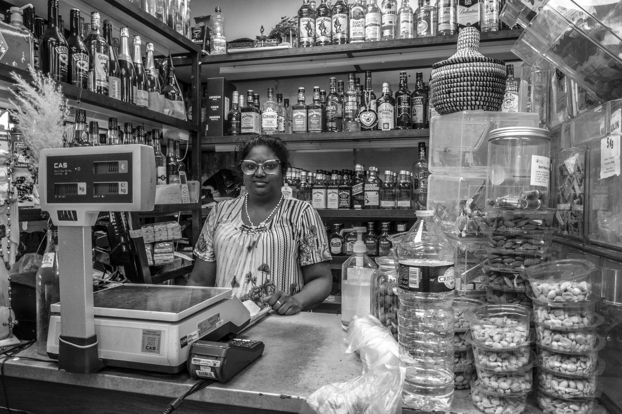 Une commerçante parmi les bocaux de son épicerie.